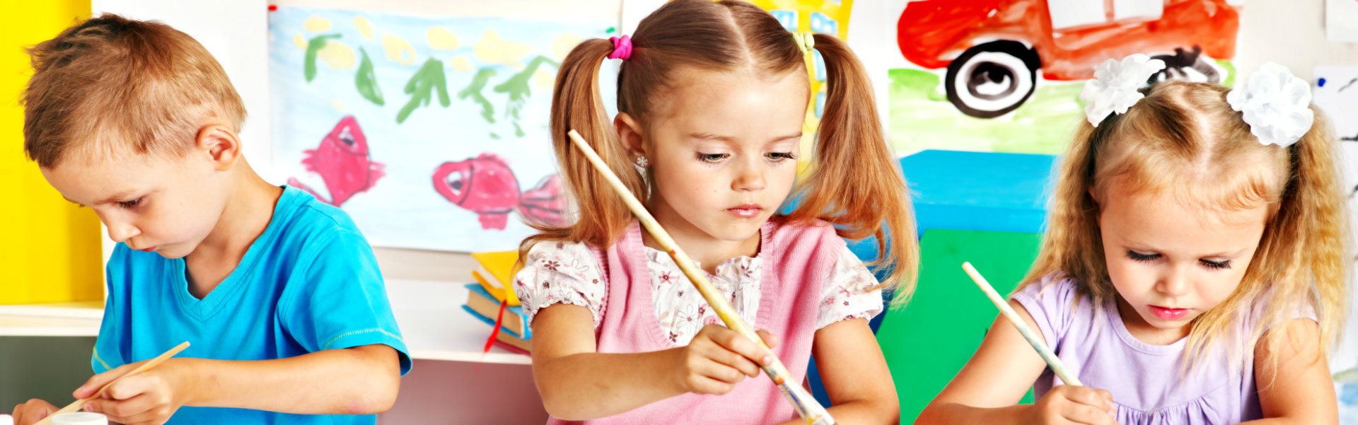 children painting at easel in school